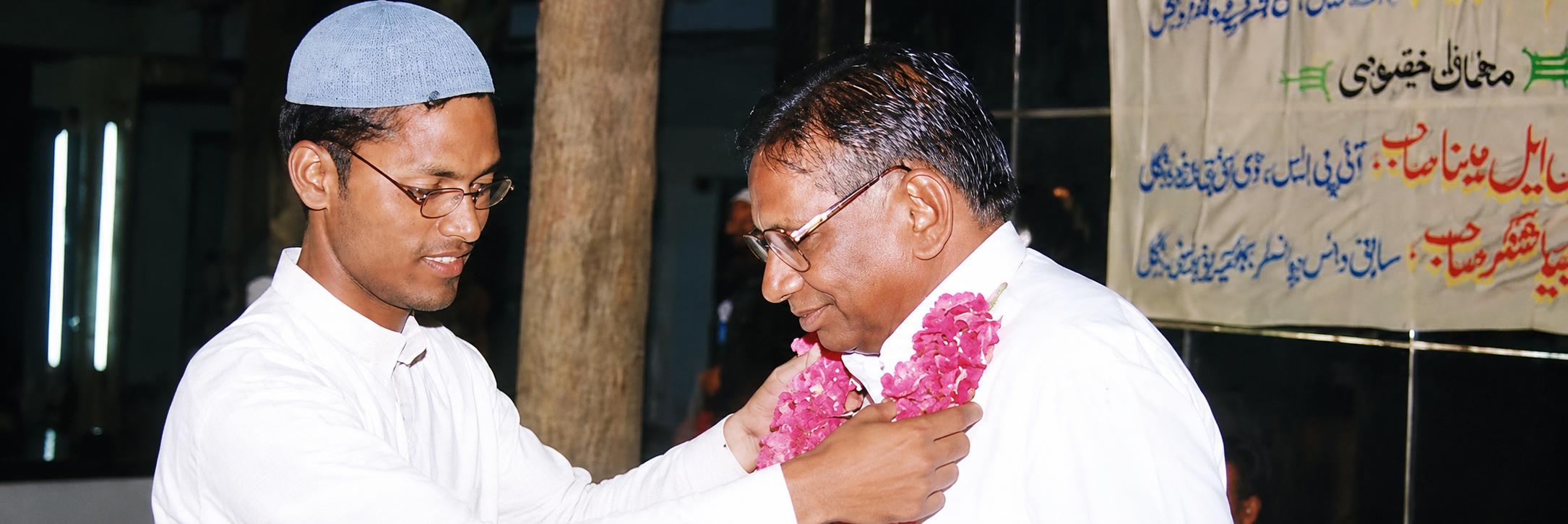 A guest being welcomed with a garland of pink flowers